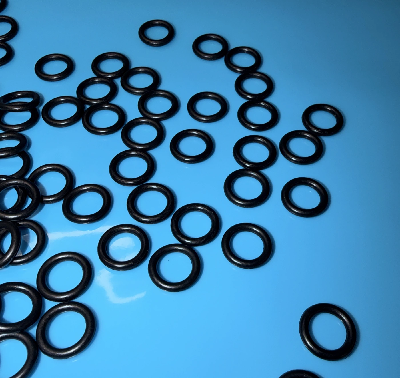 O-ring neri su un piano azzurro.